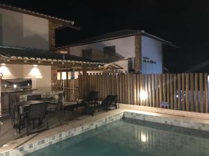 a pool with chairs and a table and a house at Conforto e Aconchego em Imbassaí/BA in Imbassai