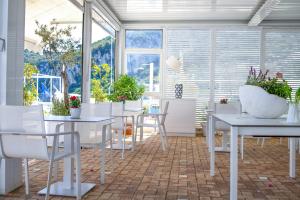 a room with white tables and chairs and windows at Relais Maresca Luxury Small Hotel & Terrace Restaurant in Capri