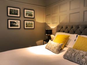 a bedroom with a large bed with a yellow pillow at Somerley House + Hut & Hot Tub in Lowestoft