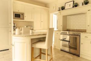 una cucina con armadi bianchi e un'isola con sedia di Somerleyton Meadows - Somerley House plus Hut & Hot Tub a Lowestoft
