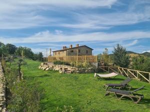 a house in the middle of a field with two picnic tables at Villa Convento Pietralunga in Pietralunga
