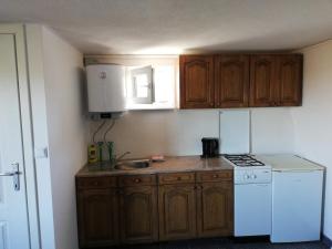 a small kitchen with wooden cabinets and a white refrigerator at Kuća za odmor Kustura in Ilok