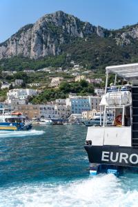 two boats in a body of water with a mountain at Relais Maresca Luxury Small Hotel & Terrace Restaurant in Capri