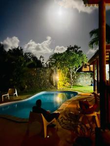 a man sitting next to a swimming pool at night at Villa Banian Île Maurice in Bain Boeuf