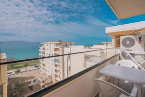 een balkon met een tafel en stoelen en de oceaan bij JD Luxury Apartments in Vlorë