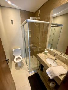 a bathroom with a toilet and a glass shower at Pousada Estrela Guia in Aparecida