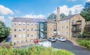 a large brick building with cars parked in a parking lot at 116 The Pond House in Holmfirth