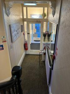 a hallway with a door leading to a room with flowers at Clifton Private Hotel in Blackpool +18 photos