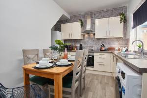 a kitchen with a wooden table and white cabinets at Stunning House wParking Sleeps7 in Darlington