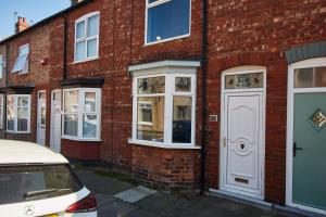 a brick building with a white door on a street at Stunning House wParking Sleeps7 in Darlington
