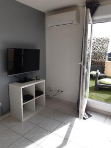 a living room with a tv and a white cabinet at Appartement Terrasse panoramique Piscine in Montpellier