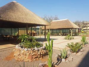 a resort with a building with grass roofs and plants at Ribbon 210's Two bedroom apartment in Gaborone
