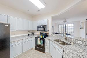 a kitchen with white cabinets and a black refrigerator at Havens 1123 in North Myrtle Beach