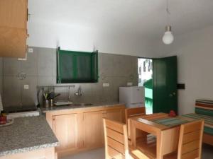 a kitchen with green cabinets and a table with chairs at Cottage na Ribeira do Paúl in Pombas