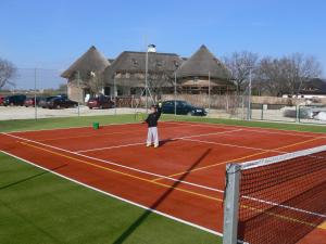 a person holding a tennis racket on a tennis court at Penzión Eko Park Piešťany in Piešťany