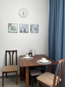 a dining room table with two chairs and a clock on the wall at ЖК Champion in Astana
