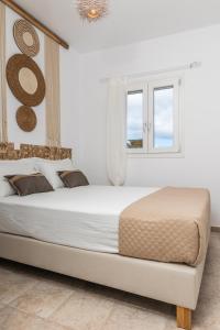 a white bedroom with a large bed and a window at Kalliston Naxos in Akrotiri