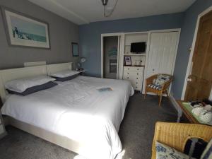 a bedroom with a white bed and a chair at Chyheira in Ruan Minor