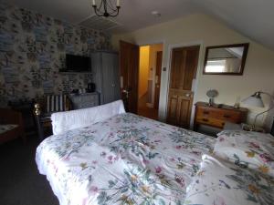 a bedroom with a bed with a floral bedspread at Chyheira in Ruan Minor