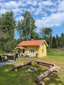 una pequeña casa amarilla con mesa de picnic y mesa en Fint torp nära vattnet med tillgång till båt., en Mellerud