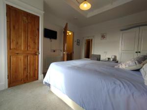 a bedroom with a large white bed with a wooden door at Chyheira in Ruan Minor