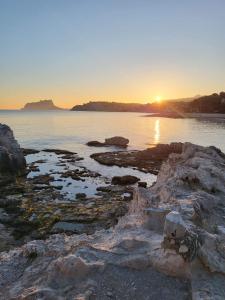 a sunset on the shore of a body of water at Apartamento Marina en Moraira in Moraira