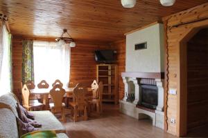 een woonkamer met een open haard en een tafel en stoelen bij Схили Карпат in Rozhanka Nizhnyaya