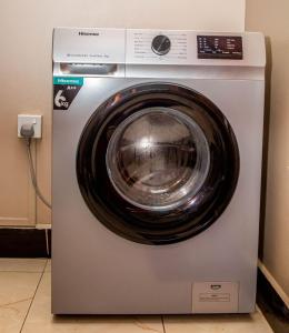 een wasmachine met een ronde deur erop bij Modern Furnished Rooms with Netflix, Kitchen, Living room , Laundry DStv and Free WiFi in Kampala