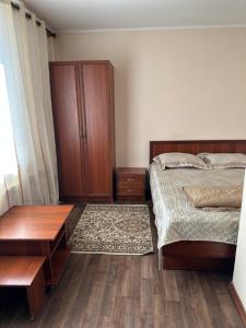 1 dormitorio con 1 cama y armario de madera en Гостевой дом "Kalinka", en Cholpon-Ata