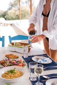 a woman pouring a glass of wine at a table with food at IosVilla at Sapounohoma in Mylopotas