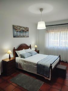 a bedroom with a bed and two lamps and a window at Pertinho do Rio in Ponte de Lima