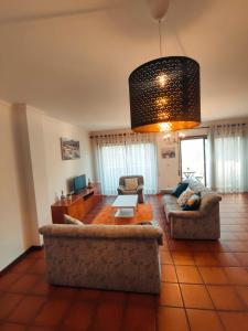 una sala de estar con 2 sofás y una lámpara de araña. en Pertinho do Rio, en Ponte de Lima