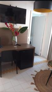 a desk with a vase of flowers on it in a room at L hibiscus in Saint-François