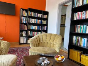 een woonkamer met 2 stoelen, een tafel en boekenkasten bij Hostel Stralsund in Stralsund