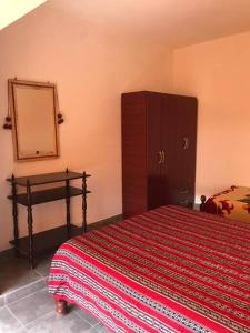 a bedroom with a bed with a dresser and a mirror at Miskysisa in Humahuaca