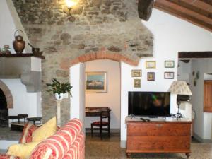 sala de estar con sofá y TV en Farmhouse in Cortona wit garden and pool, en Cortona