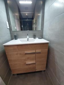 ein Bad mit einem Waschbecken und einem Spiegel in der Unterkunft duplex cocooning à 10 min à pied du centre ville in Saint-Nabord