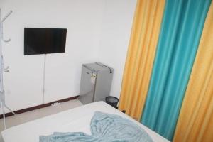 um quarto com uma cama, uma televisão e cortinas em Plateau Bedroom & Chambre - Praia Center 1 em Praia