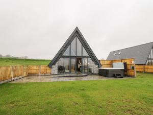 een huis met een zwart dak op een groen veld bij Brecknock Cheviot - The Sheepfold in Llandrindod Wells