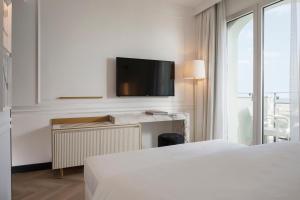 a hotel room with two beds and a flat screen tv at Hotel De Londres in Rimini