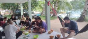 Eine Gruppe von Menschen, die an einem Tisch sitzen und Essen essen. in der Unterkunft Homestay Buang Sari in Gresik