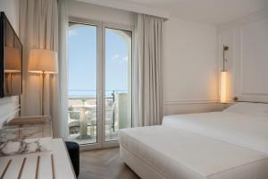 a hotel room with two beds and a large window at Hotel De Londres in Rimini
