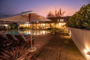 a swimming pool with two chairs and an umbrella at Graskop Hotel in Graskop