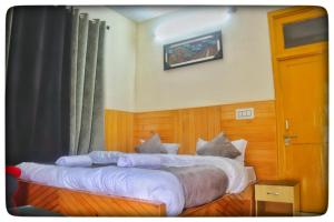 een slaapkamer met een groot bed met witte lakens bij Kullu Manali Homestay in Kulu