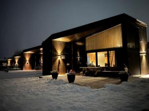 un edificio con nieve delante de él por la noche en Attraktiv & smart funkishytte på Nes Strandhager., en Årnes