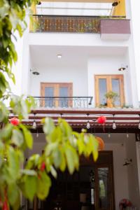 un edificio con un balcón con flores rojas. en Trú Homestay Huế, en Thôn Dương Xuân Hạ