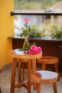 un jarrón de flores en una mesa con dos taburetes en Trú Homestay Huế, en Thôn Dương Xuân Hạ
