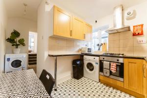 une cuisine équipée d'un lave-linge et d'un lave-linge/sèche-linge. dans l'établissement Mile end Double rooms 86a, à Londres