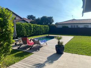 a backyard with two chairs and a swimming pool at Hiru Alabak - Maison à Biarritz, piscine, jardin, 8 personnes in Biarritz