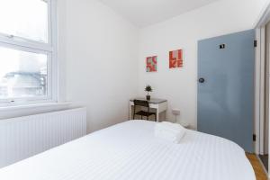 a white bedroom with a white bed and a window at Mile end Double rooms 86a in London